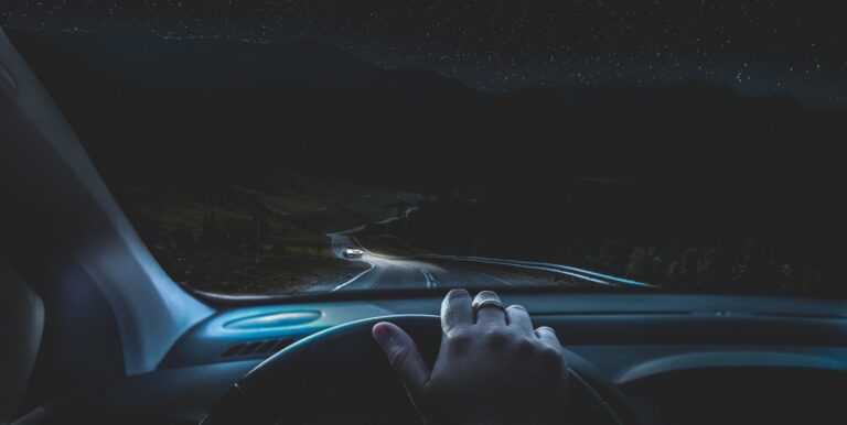 Derselbe Blick nach Einbruch der Dunkelheit: Strasse im Scheinwerferlicht, entgegenkommendes Auto mit Licht